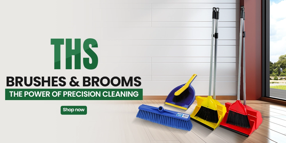 Colorful dustpan-and-broom sets standing on a clean wood floor beside a blue push broom, promoting THS precision cleaning tools in a bright room.